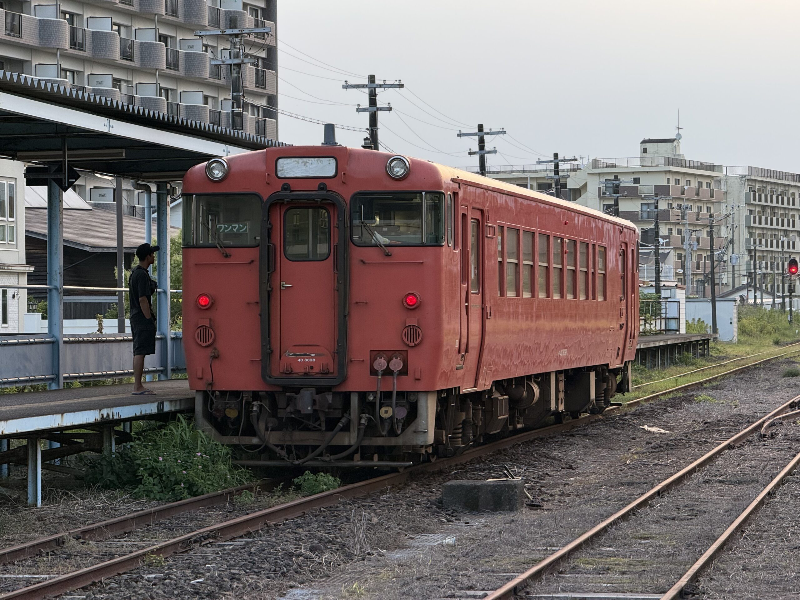 志布志駅 キハ40 8098 首都圏色 25.2℃ 湿度高い 旅人2人 帰省客 見送り1人