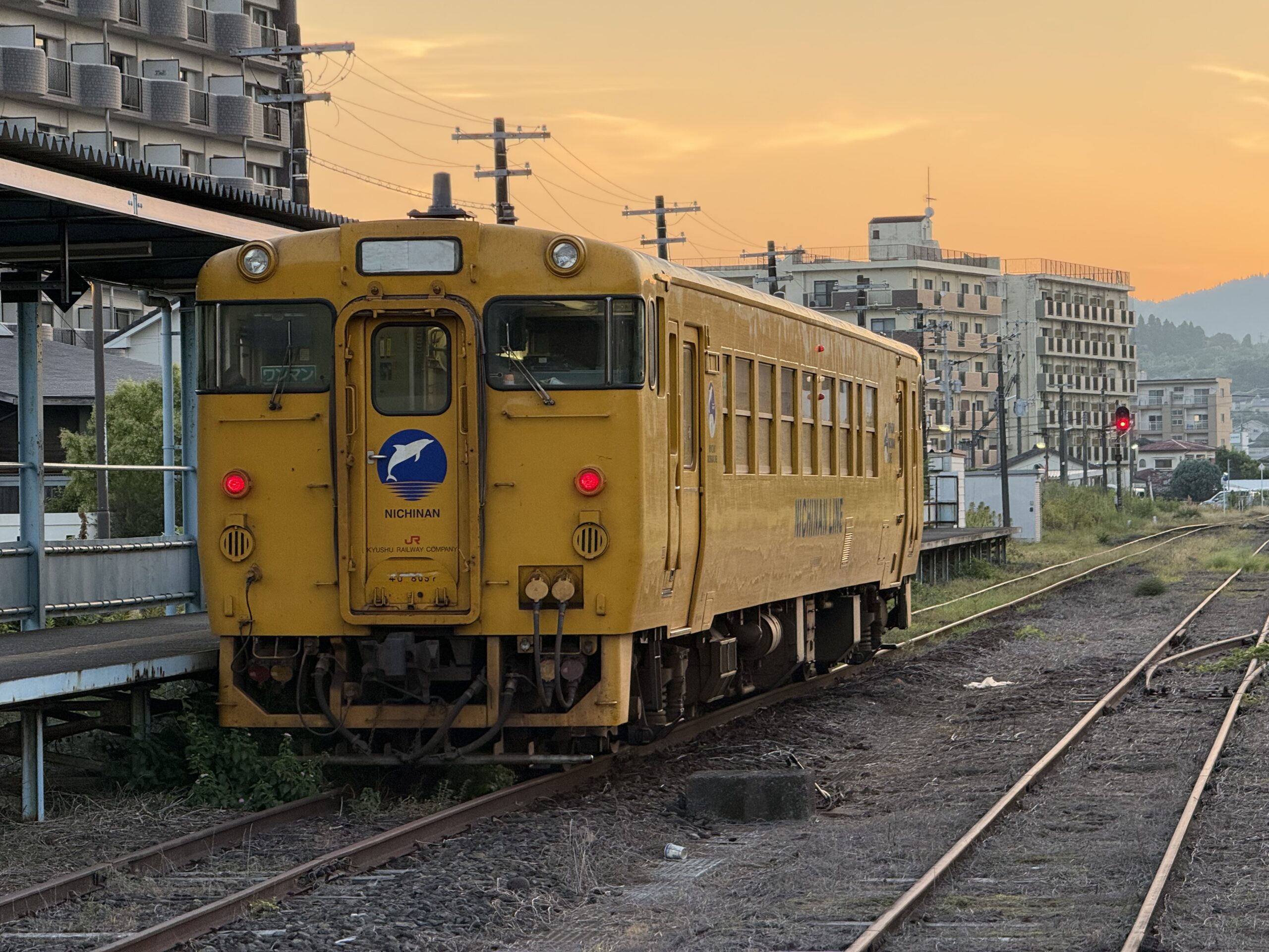 志布志駅 キハ40 8097 日南色 24.0℃ ひんやり感 駅舎外ベンチ乗車待ち1人